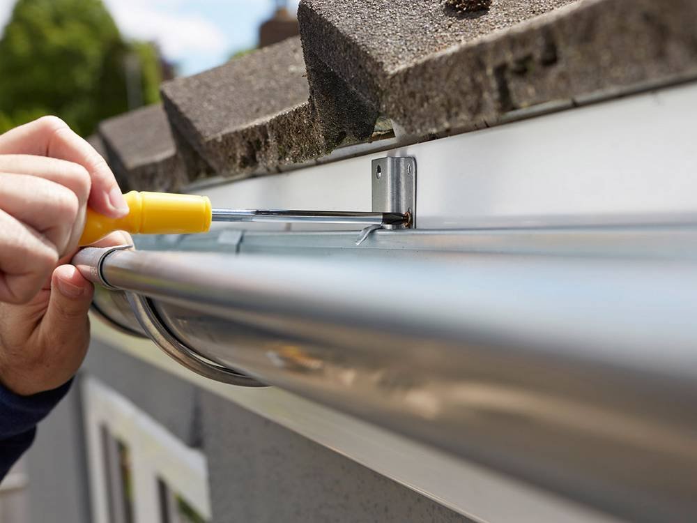 Gutter repair Limerick close up of man replacing guttering on exterior of house